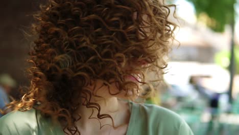 portrait of a pretty ginger girl with professional pink makeup smiling. she is having attractive look. wearing green blouse, twisting her head and laughing cheerfuly to the camera, showing her tongue. outdoors. slow motion