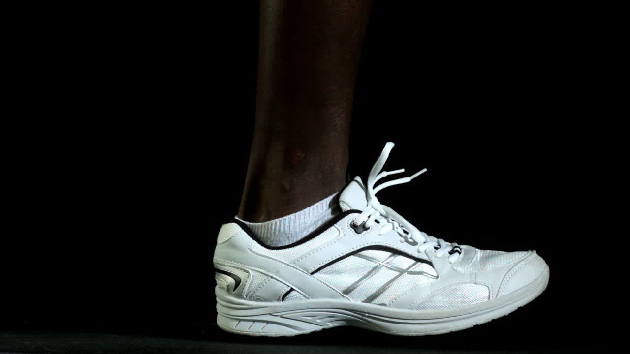 piernas en zapatillas de correr corriendo contra un fondo negro