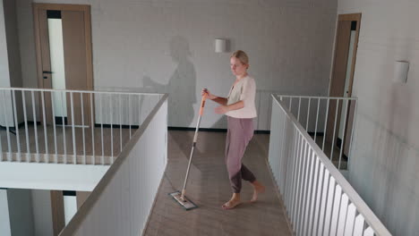 woman mopping a wooden floor in a modern apartment