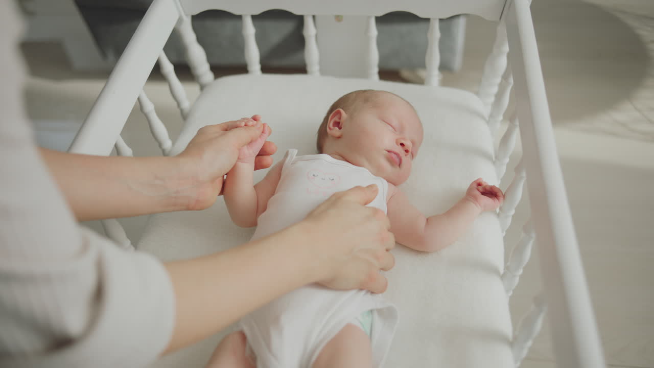 Madre che tiene delicatamente e accudisce il neonato in una culla bianca