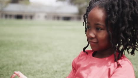 young girl smiling outdoors on school field, enjoying sunny day, copy space