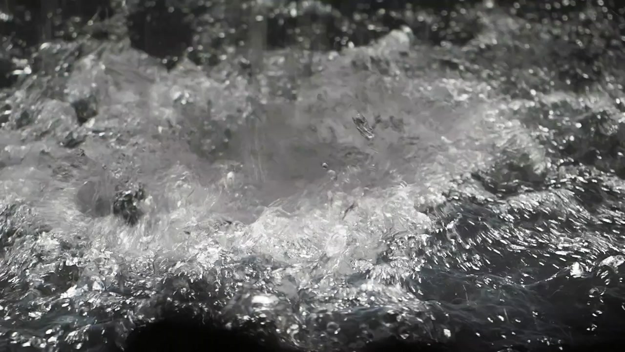 Close-Up of Water Splashing and Rippling on a Dark Surface