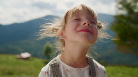 portrait girl enjoying sunlight in mountains. child putting face under sunshine.