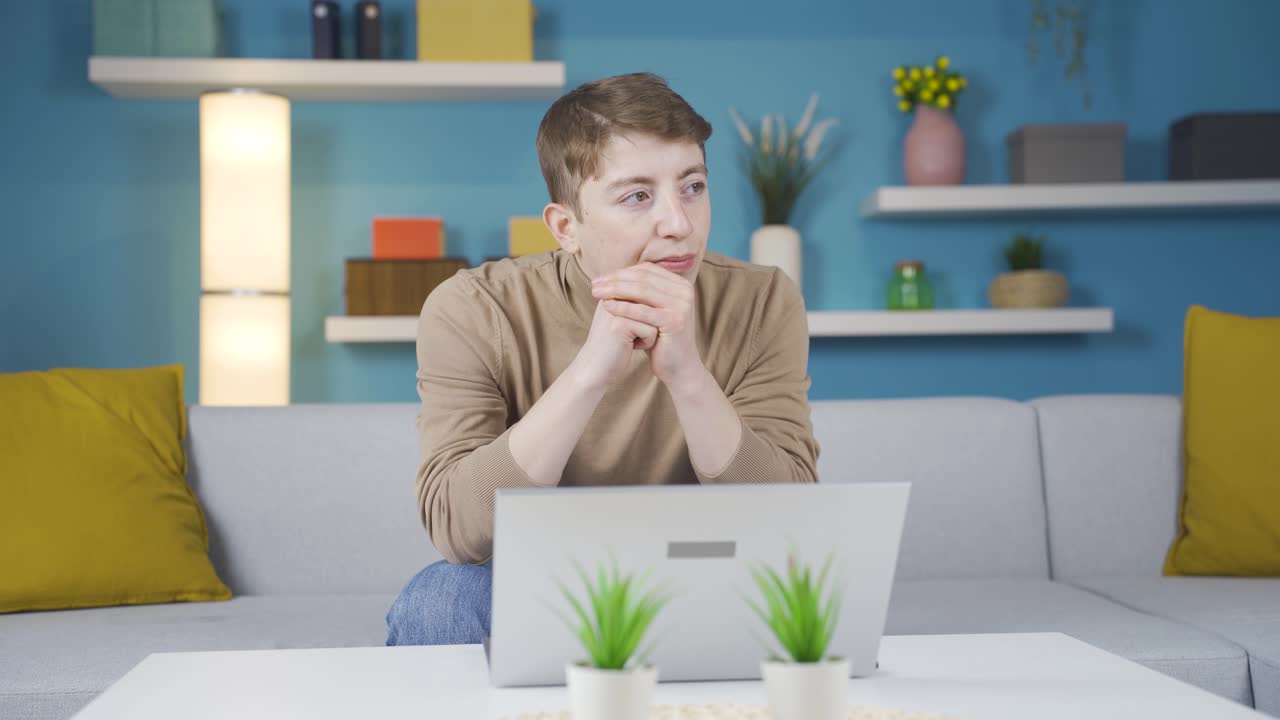 un adolescente reflexivo usando una computadora portátil en casa.