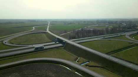 aerial view, the drone flies along infinity highway road interchange with light urban traffic speeding on the road