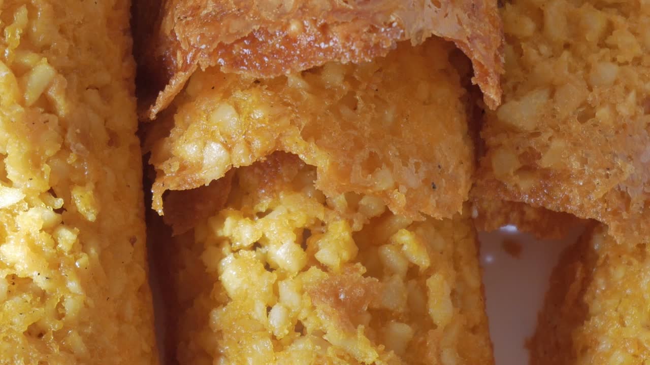 Smooth pan right of crunchy almond tiles with toasted surface under natural light