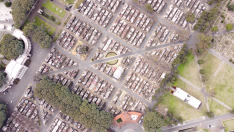 toma aérea de pájaros de automóviles que circulan por la carretera entre el cementerio gigante en buenos aires durante la luz del sol