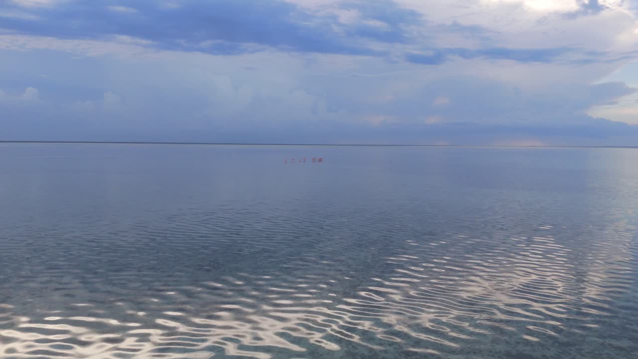 Fly forward over water with dense clouds blue skies in Quintana Roo