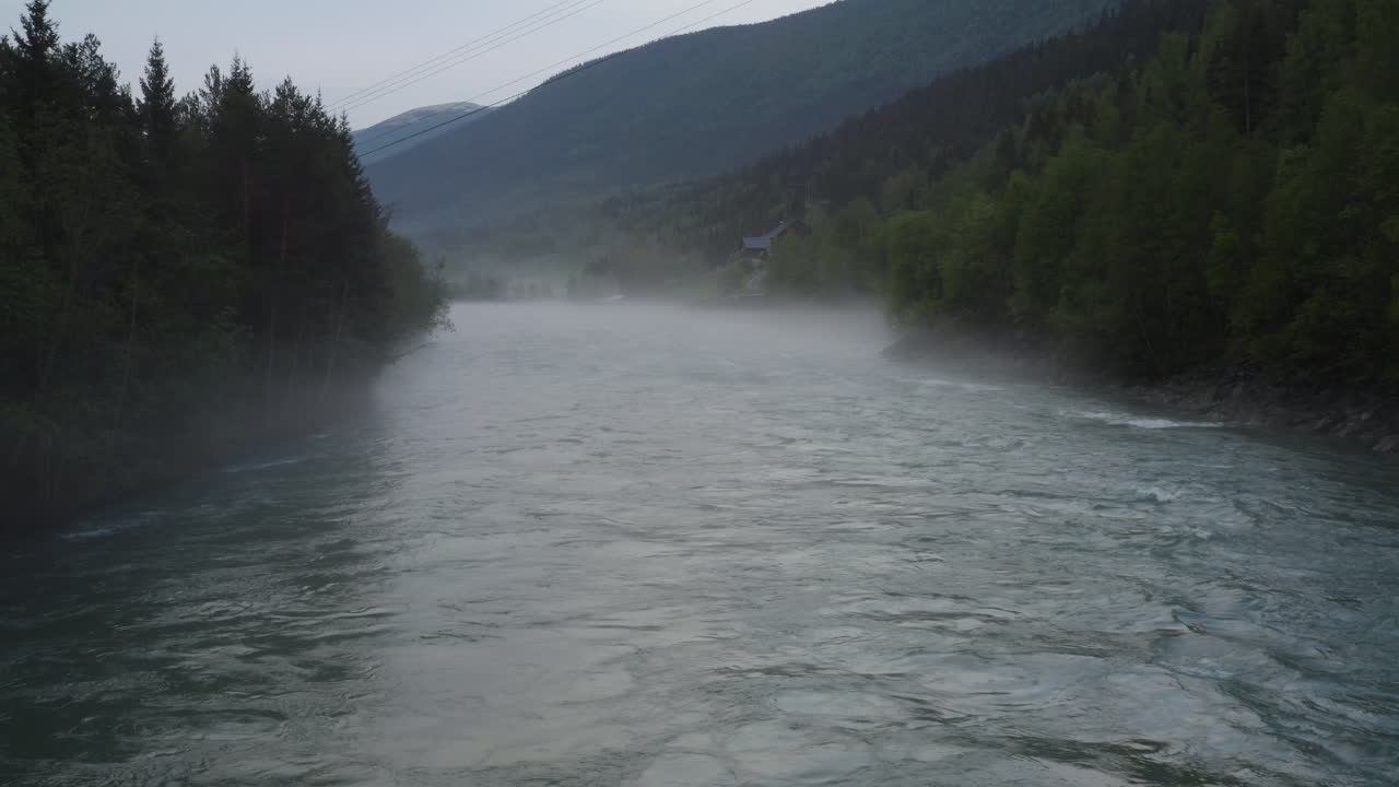 Flight over a foggy river. The mist is hanging low over the landscape creating a dark mystical mood over the whole scene.