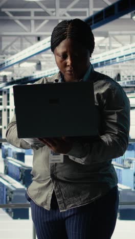 vertical video data center admin checks ai dashboard using laptop during rigs systems review