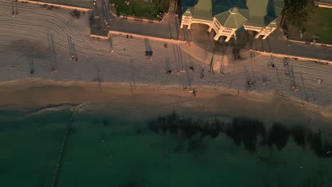 Gente-A-Lo-Largo-De-La-Playa-De-Cotesloe-En-Australia-Al-Atardecer,-Vista-Aérea-De-Arriba-Hacia-Abajo-De-La-Costa-Arenosa