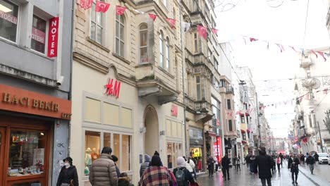 people walking down a busy street in istanbul with stores on both sides.