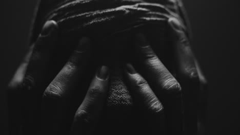 a mummified woman against the dark background in keeps her hands on her face the powerful pose full of despair
