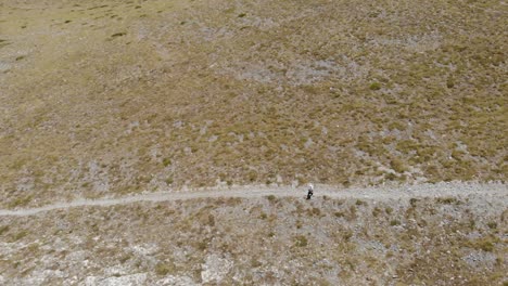 toma aérea de un hombre caminando, caminando solo en la montaña griega kissavos en la región de tesalia, vista de drones, ruta en la montaña, estilo de vida deportivo, manera saludable de dejar el paisaje marrón