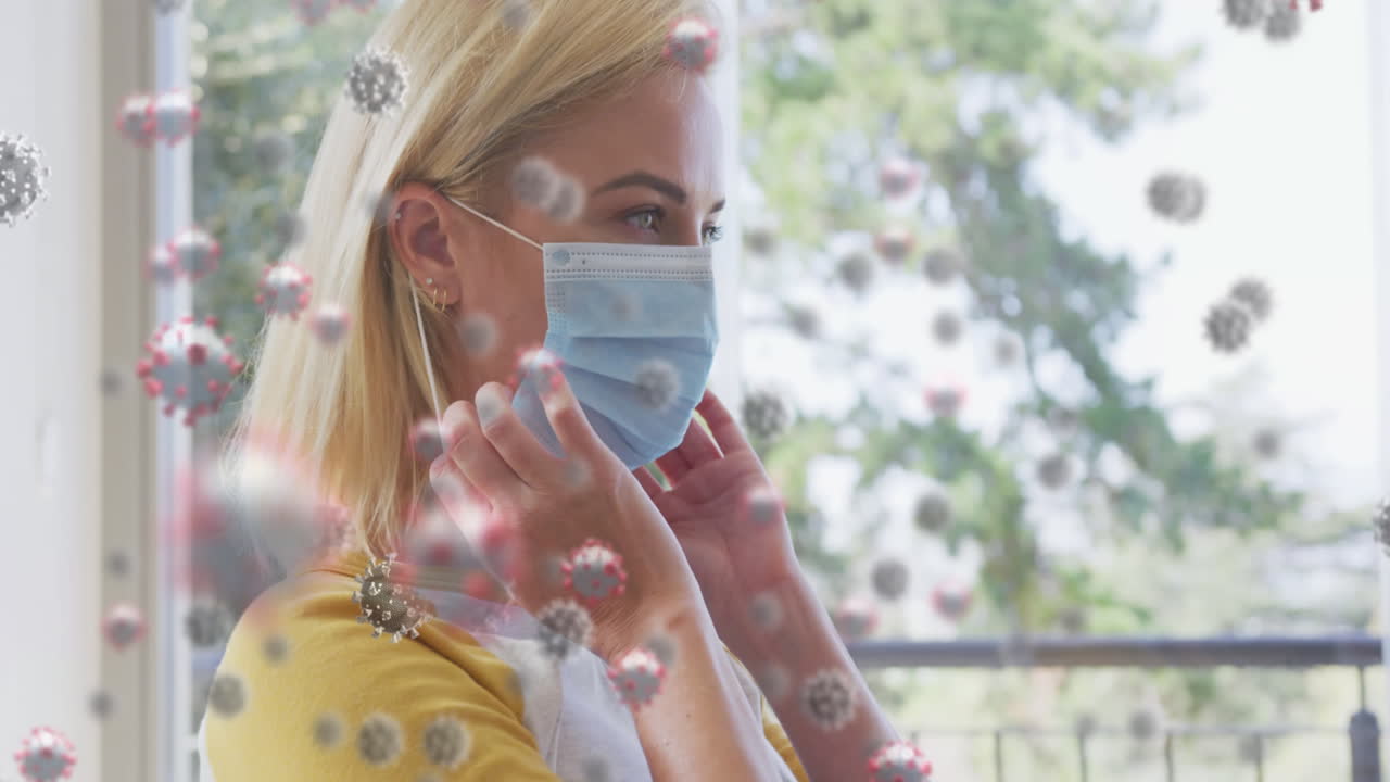 Animación de células de COVID-19 sobre mujer rubia caucásica poniéndose una mascarilla facial.