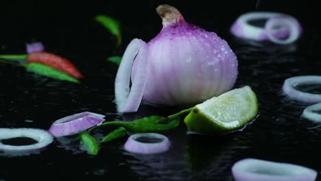 water splash on fresh whole onion and onion rings, chili peppers, and lime