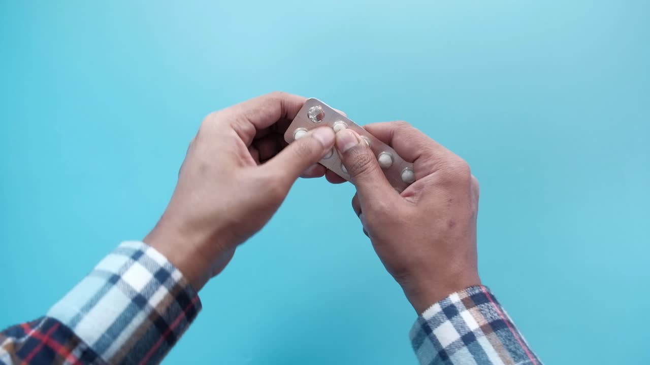 약의 블리스터 패키지를 열고 있는 사람