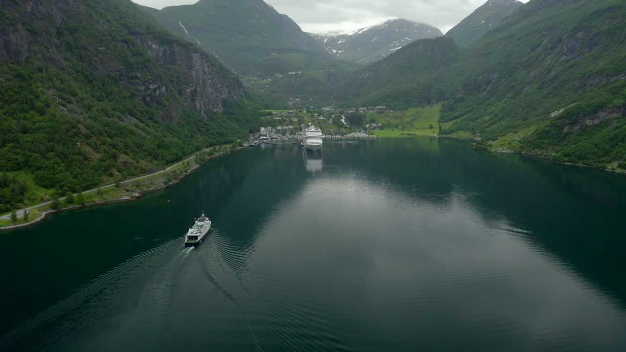 filmagem real de drone voando no fiorde de geiranger em direção à cidade seguindo uma balsa