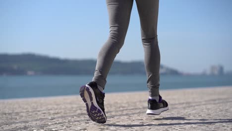 legs of sporty young woman running at riverside