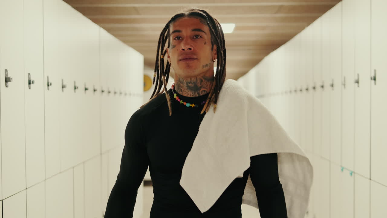 Uomo con dreadlocks e tatuaggi che cammina nello spogliatoio