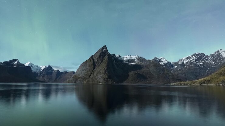 Aurora boreale e montagne illuminate dalla luna piena a Hamnøy, Lofoten