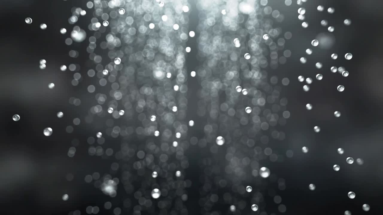 Colonna di goccioline che cadono dall'alto al centro dell'inquadratura e scivolano verso il basso, formando un effetto bokeh