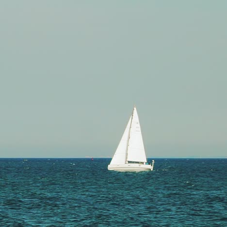 white sailboat is sailing on the sea far from the coast in the summer. slow motion