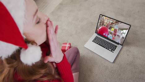 mujer caucásica con sombrero de santa en una llamada de video portátil durante la navidad en casa
