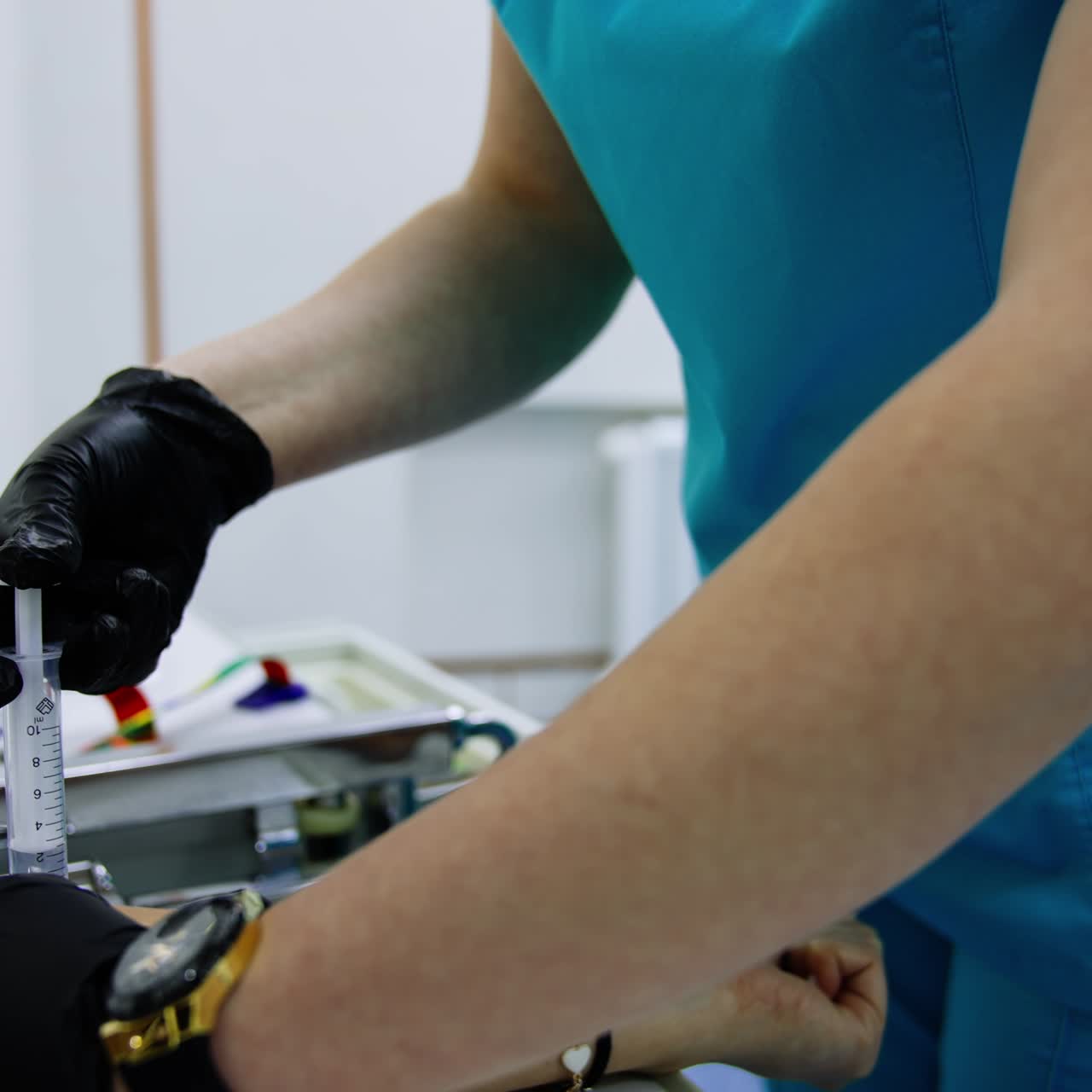Male medic in black latex gloves giving a shot. Doctor inserting medicines into a catheter in patient's hand