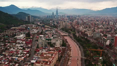 drone establishing shot of santiago chile with the financial center and the snowy andes mountain range in the background, costanera tower