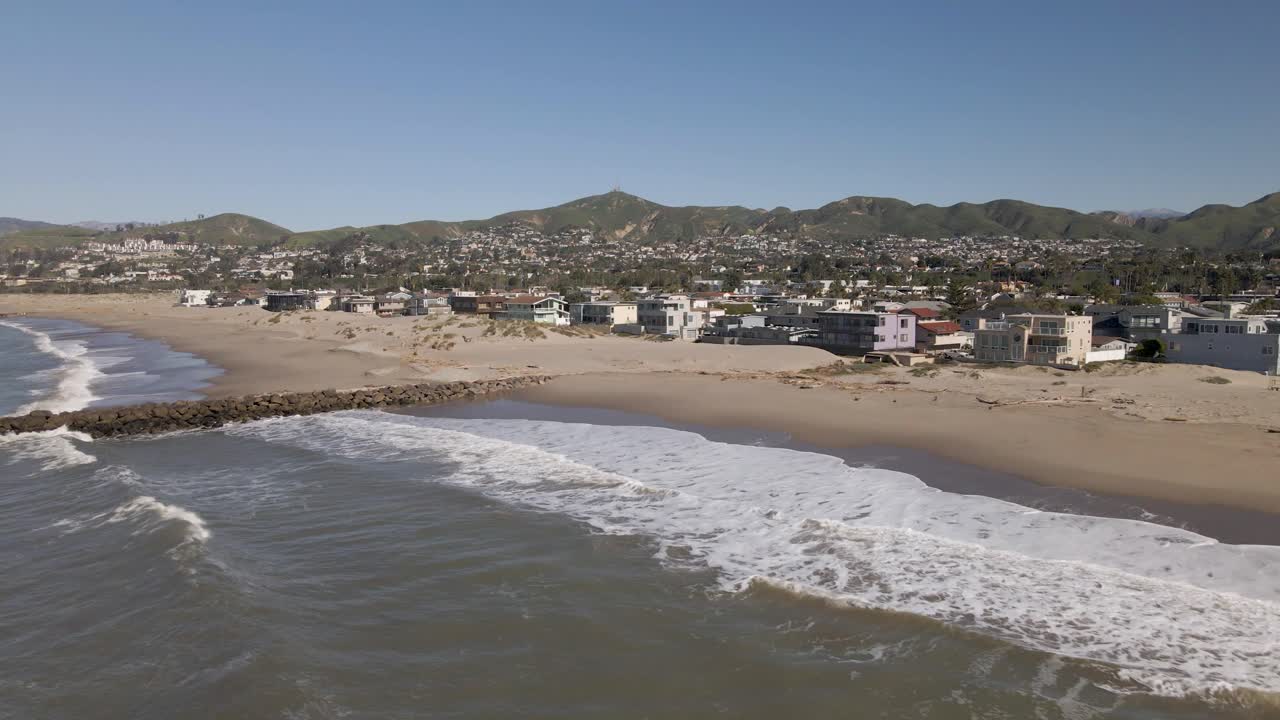 vuelo de drones desde la playa de ventura a la vista de la ciudad, capturando olas tranquilas, cielos despejados y casas frente a la playa