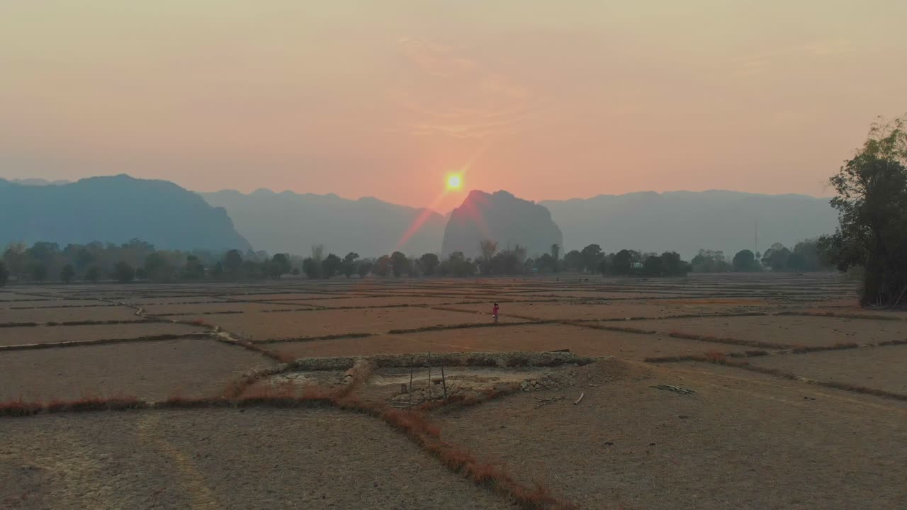 Uomo in un campo coltivato di Thakhek al crepuscolo. Laos, Khammouane
