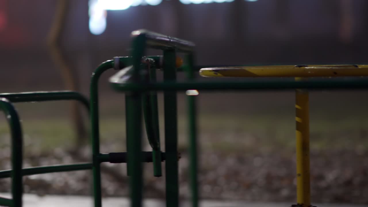 가을 밤에 시내 공원의 빈 어린이 놀이터에서 은 카루셀이 회전하고 있습니다.