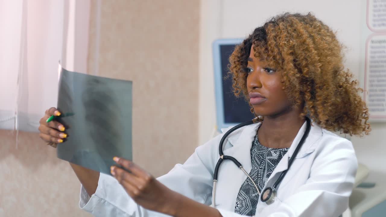una doctora afroamericana examina las radiografías de los pulmones de un paciente con coronavirus. concepto de medicina, atención médica y personas