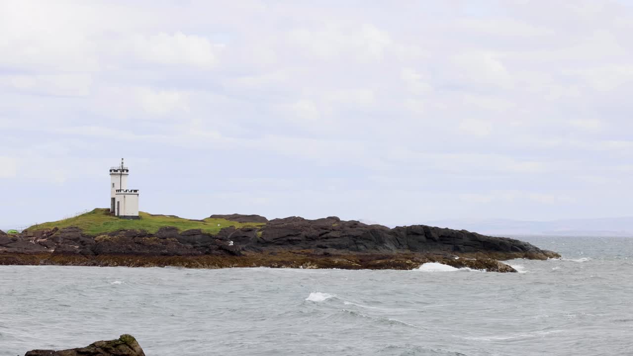 faro en una isla rocosa con olas que se estrellan