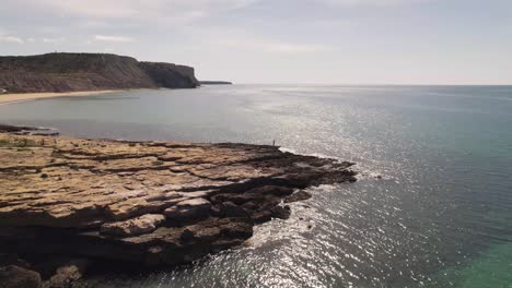 Fly-over-alongside-rocky-Algarve-shoreline-revealing-Praia-da-Luz---Aerial