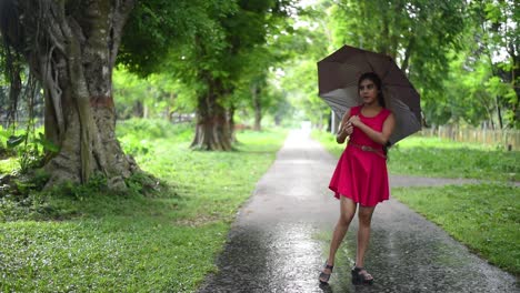 a beautiful romantic girl is rolling and playing with her umbrella on road in rainy season, slow motion