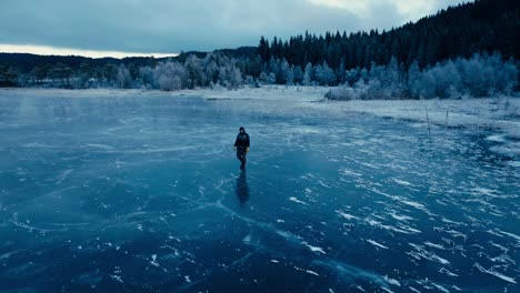 Indre-Fosen,-Condado-De-Trondelag,-Noruega---Un-Hombre-Paseando-Por-La-Superficie-Helada-De-Omundvatnet---Disparo-De-Un-Dron-En-órbita