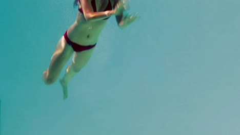 Pretty-brunette-diving-into-swimming-pool-and-waving