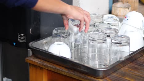 persona recogiendo vasos de una bandeja