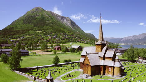 iglesia de madera de lom con cementerio en un día soleado con vistas a la montaña en lom, condado de innlandet, noruega