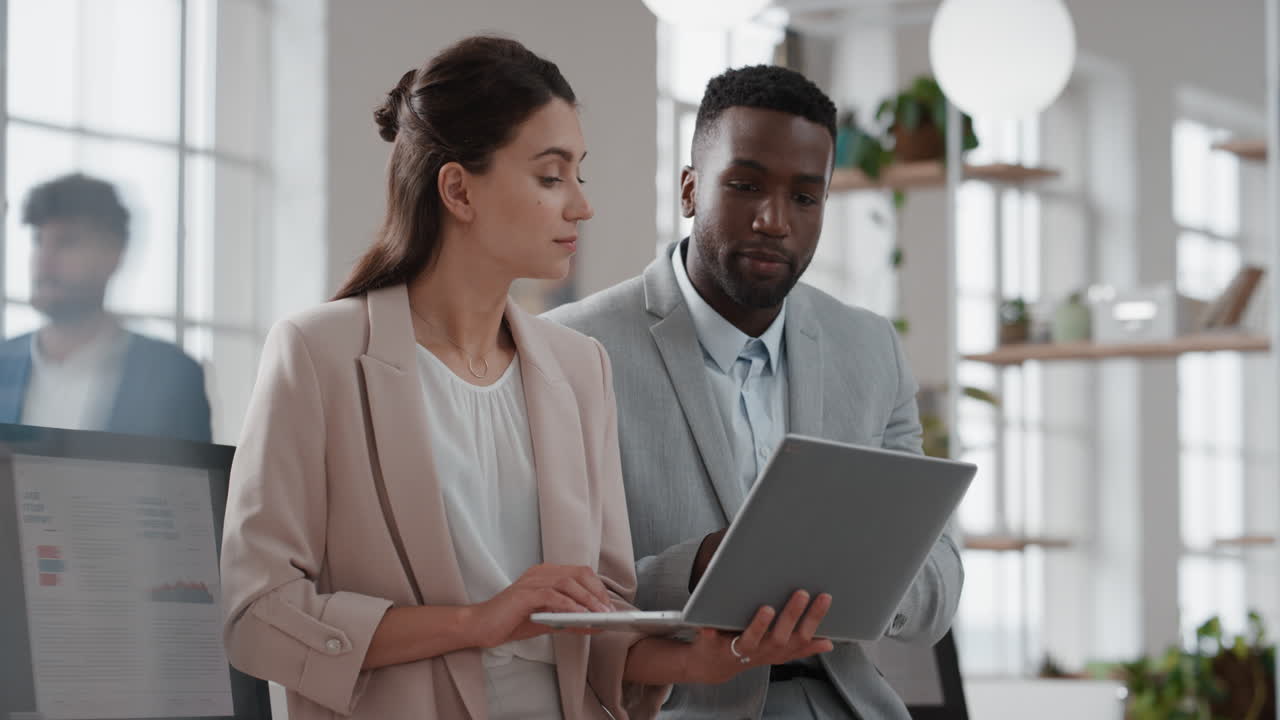 young team leader woman brainstorming with businessman colleague using laptop computer showing ideas pointing at screen working together in office
