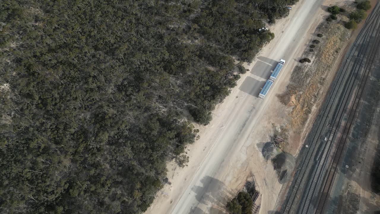 Un enorme camion per il trasporto di grano con rimorchio viaggia accanto alla ferrovia in Australia