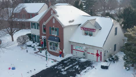 winter snow falls on house decorated for christmas season