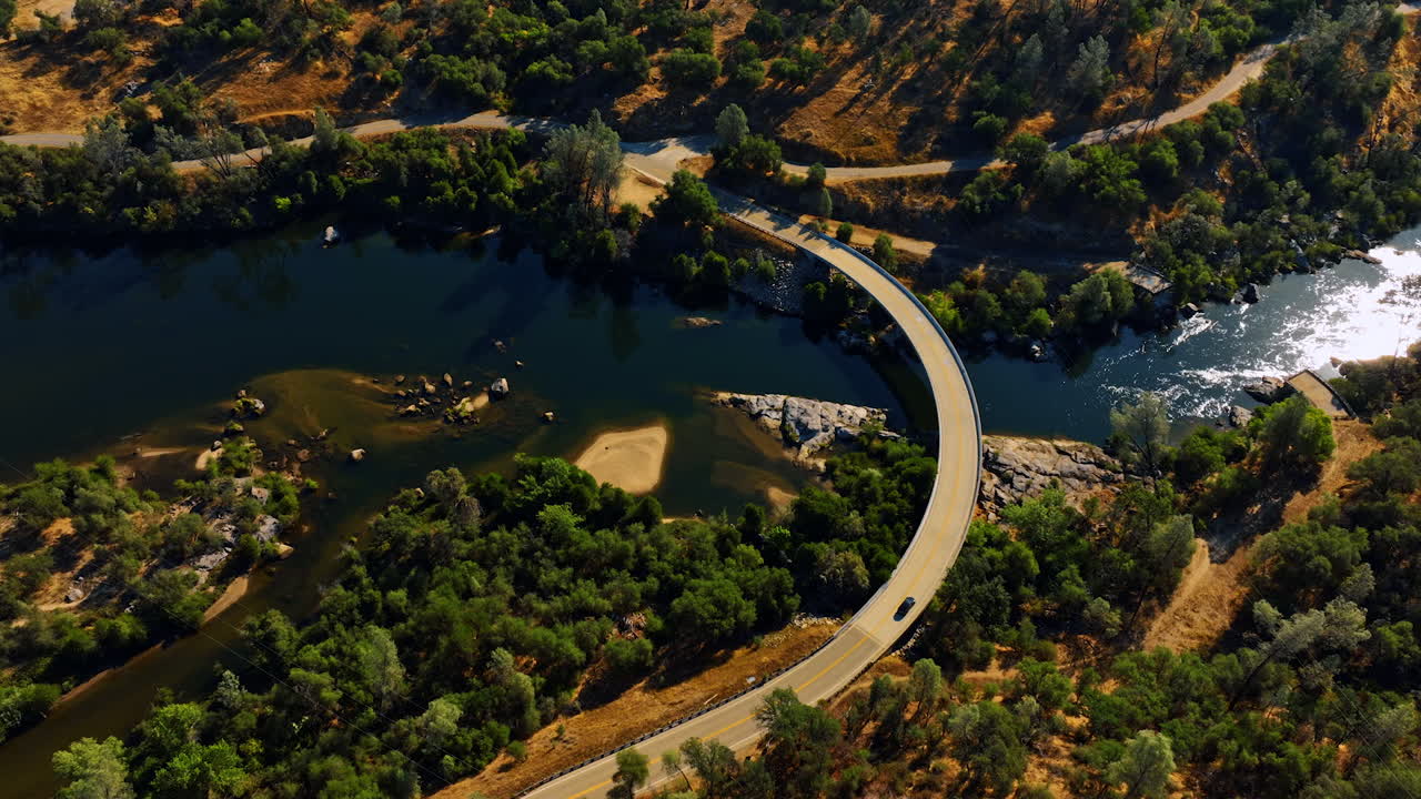 Following the car going by the highway crossing the lake. Sunny panorama of Sierra National Forest, California, USA from top.