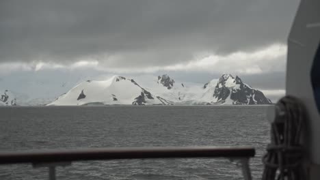 Vista-Desde-El-Barco,-Sobre-La-Baranda,-Mirando-A-La-Montaña-En-La-Costa-Cubierta-De-Nieve-Y-Hielo