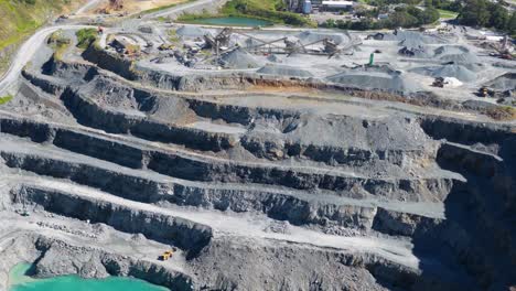 aerial footage of a terraced quarry with turquoise water, showcasing industrial activity under bright daylight in gold coast, australia