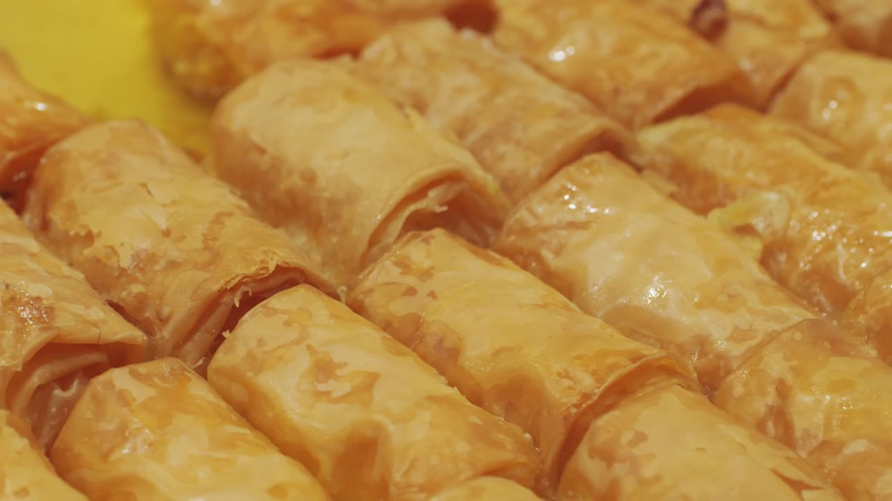 Close-up view of golden, flaky, honey-glazed pastries arranged in rows. Perfectly baked sweet delights.