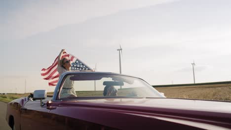 Video-of-happy-couple-driving-a-car-with-a-flag