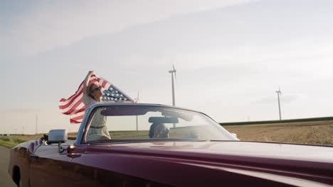 vídeo de um casal feliz a conduzir um carro com uma bandeira